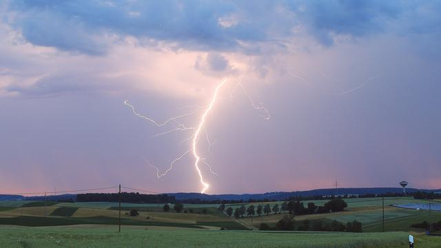 Ein Blitz zuckt bei einem Gewitter aus einer Wolke auf die Erde.