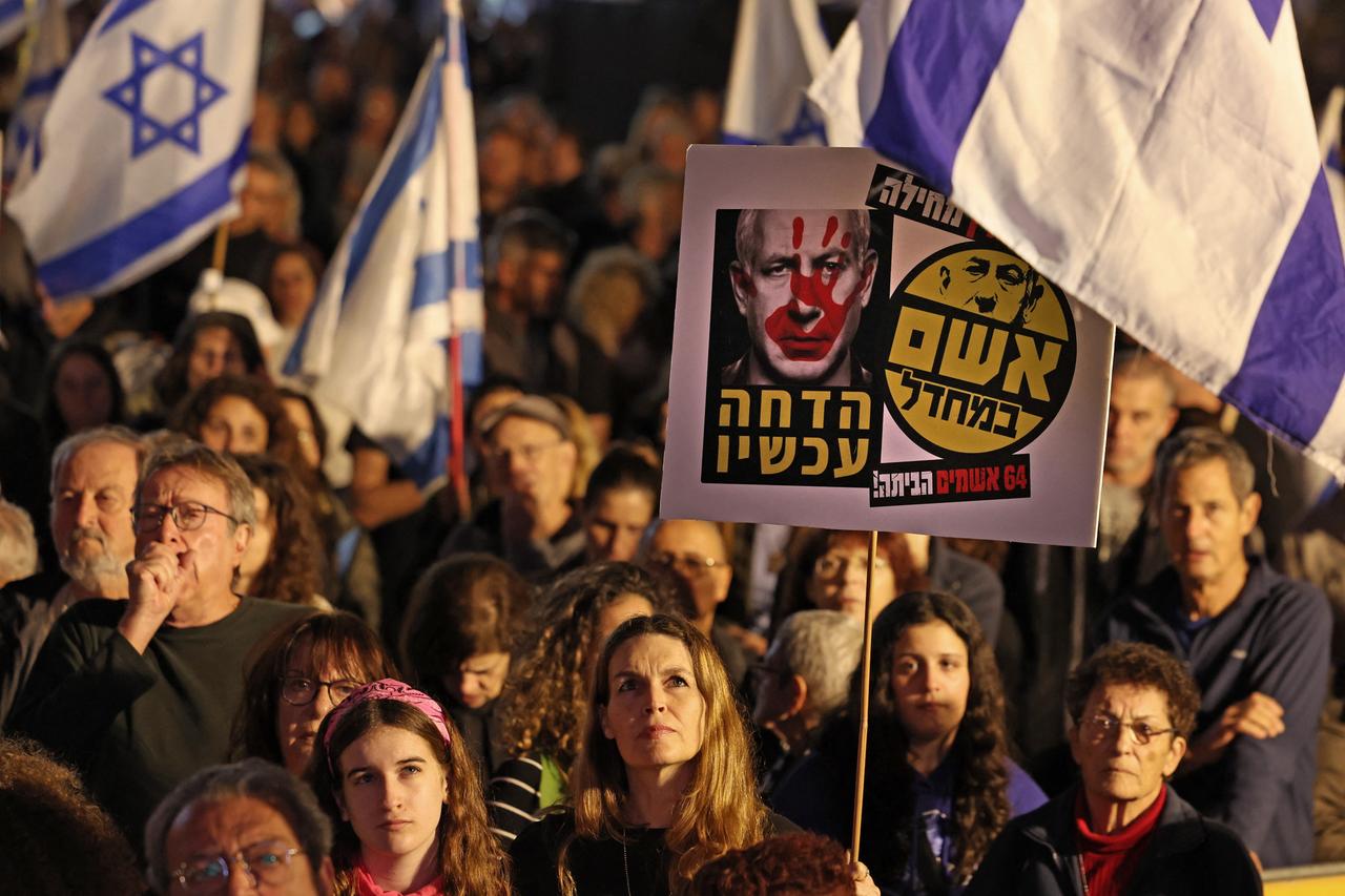 Teilnehmer an einer Anti-Regierungs-Demonstration halten in der israelischen Großstadt Tel Aviv Landesflaggen und politische Botschaften in die Höhe.