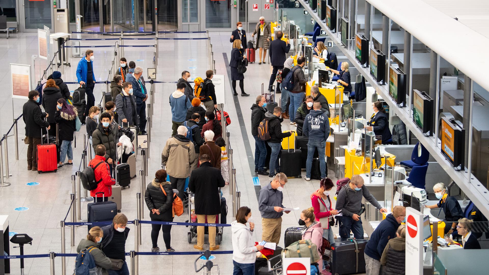 Blick von oben auf eine Schlange von Menschen vor mehreren Flugschaltern.