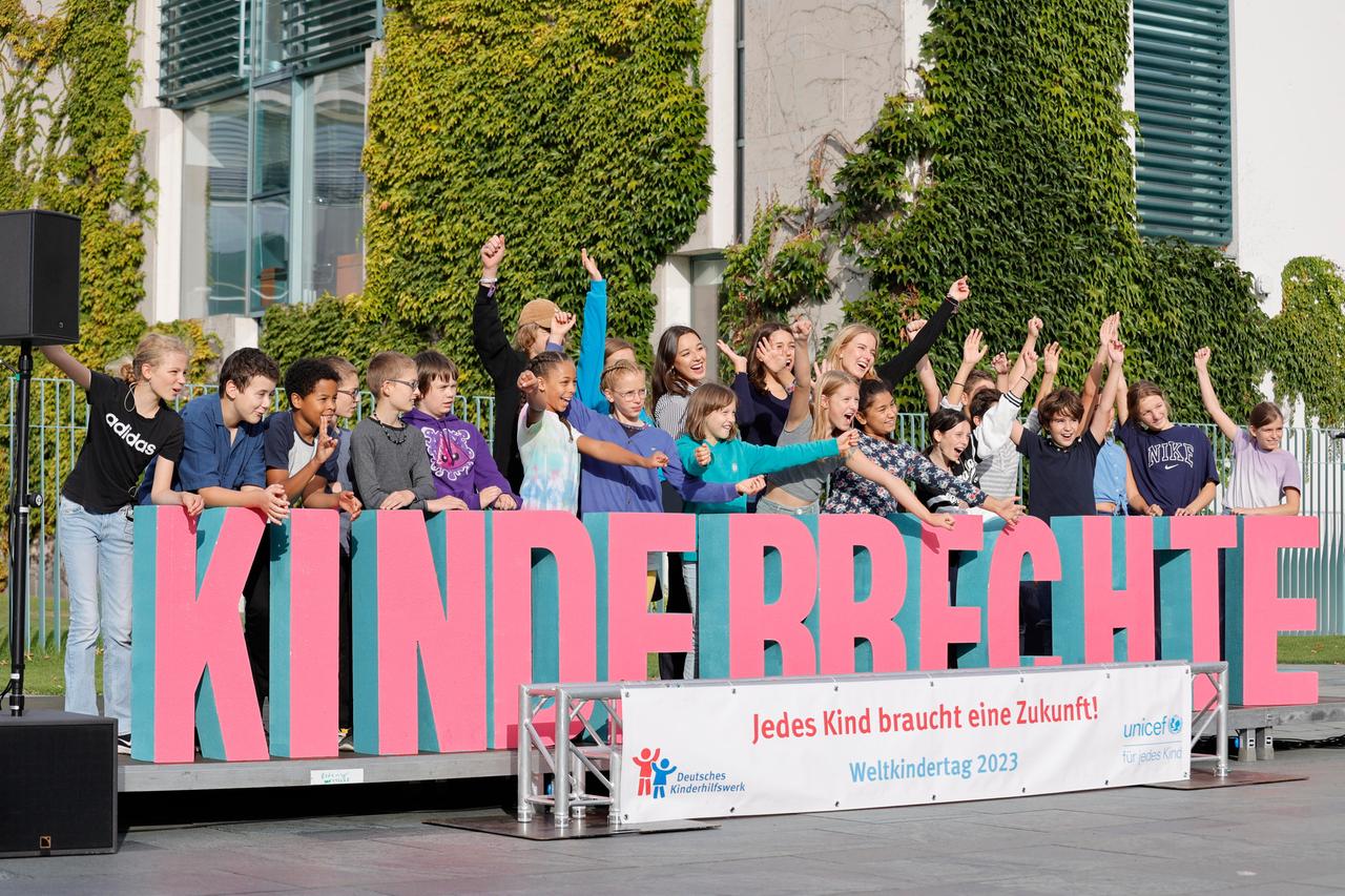 Kinder vor dem Bundeskanzleramt: sie stehen hinter einer Reihe von großen Buchstaben. Die Buchstaben formen das Wort "Kinderrechte". Davor ist ein Transparent mit der Aufschrift "Jedes Kind braucht eine Zukunft! Weltkindertag 2023"