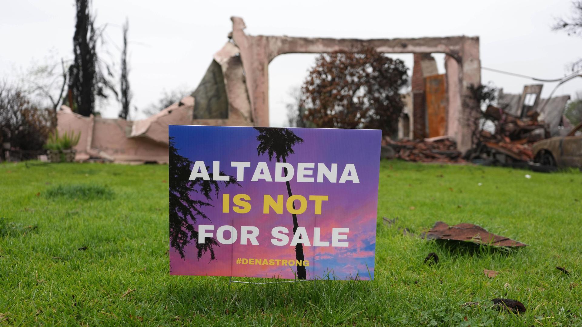 Im Garten vor der Ruine eines Wohnhauses steht ein Schild mit der Aufschrift "Altadena ist not for Sale". Im Garten vor der Ruine eines Wohnhauses steht ein Schild mit der Aufschrift "Altadena ist not for Sale".