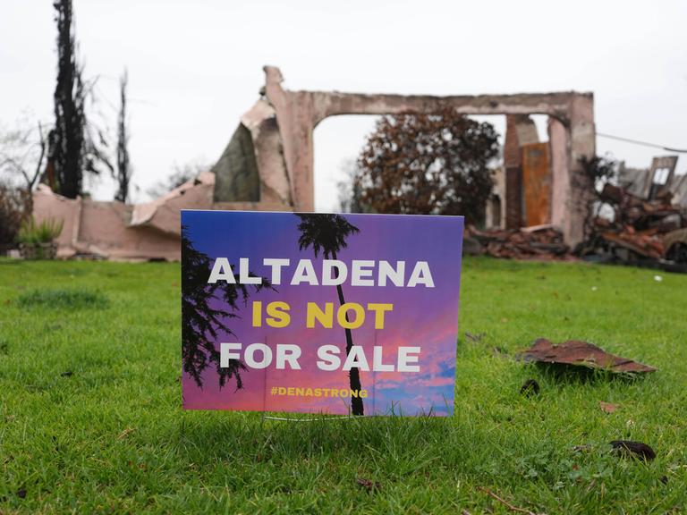 Im Garten vor der Ruine eines Wohnhauses steht ein Schild mit der Aufschrift "Altadena ist not for Sale".