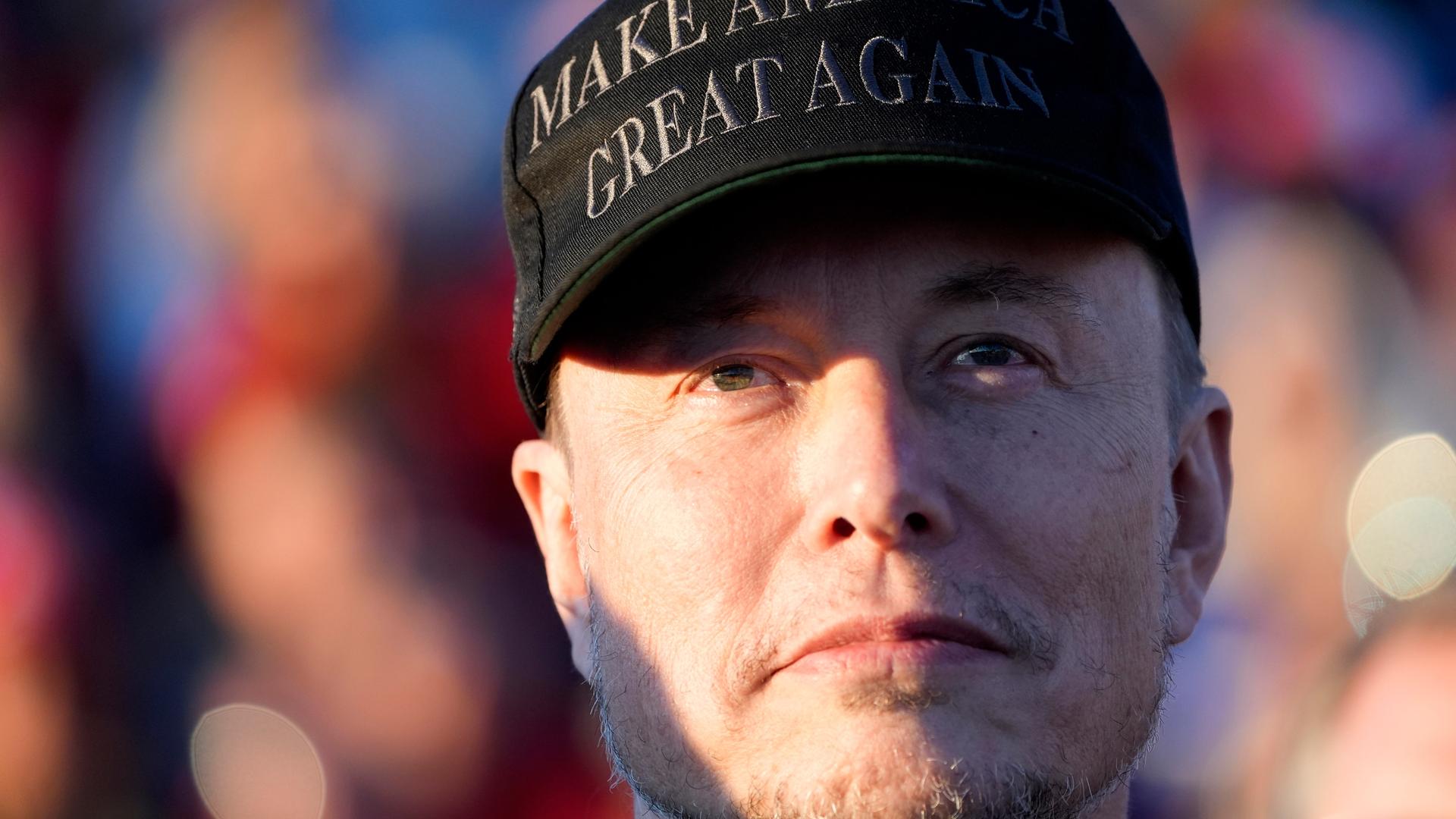 Elon Musk trägt eine Kappe mit der Aufschrift "make america great again".