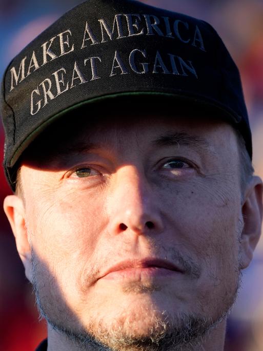 Elon Musk trägt eine Kappe mit der Aufschrift "make america great again".