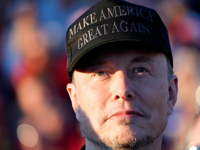 Elon Musk trägt eine Kappe mit der Aufschrift "make america great again".