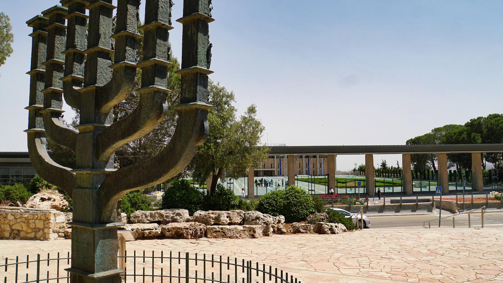 Übelebensgroße Skulptur einer Menora, eines jüdischen Leuchters, der vor der Knesset in Jerusalem, Israel, steht. Der Himmel ist klar.