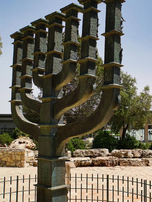 Übelebensgroße Skulptur einer Menora, eines jüdischen Leuchters, der vor der Knesset in Jerusalem, Israel, steht. Der Himmel ist klar.