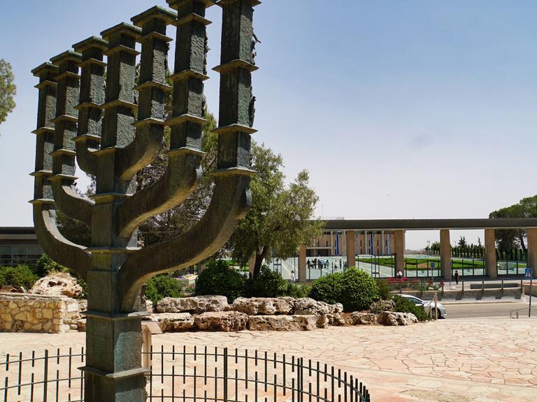 Übelebensgroße Skulptur einer Menora, eines jüdischen Leuchters, der vor der Knesset in Jerusalem, Israel, steht. Der Himmel ist klar.