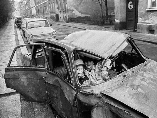 Lachende Kinder sitzen in einem Autowrack in der Steinstraße, Berlin 1990. Lachende Kinder sitzen in einem Autowrack in der Steinstraße, Berlin 1990.