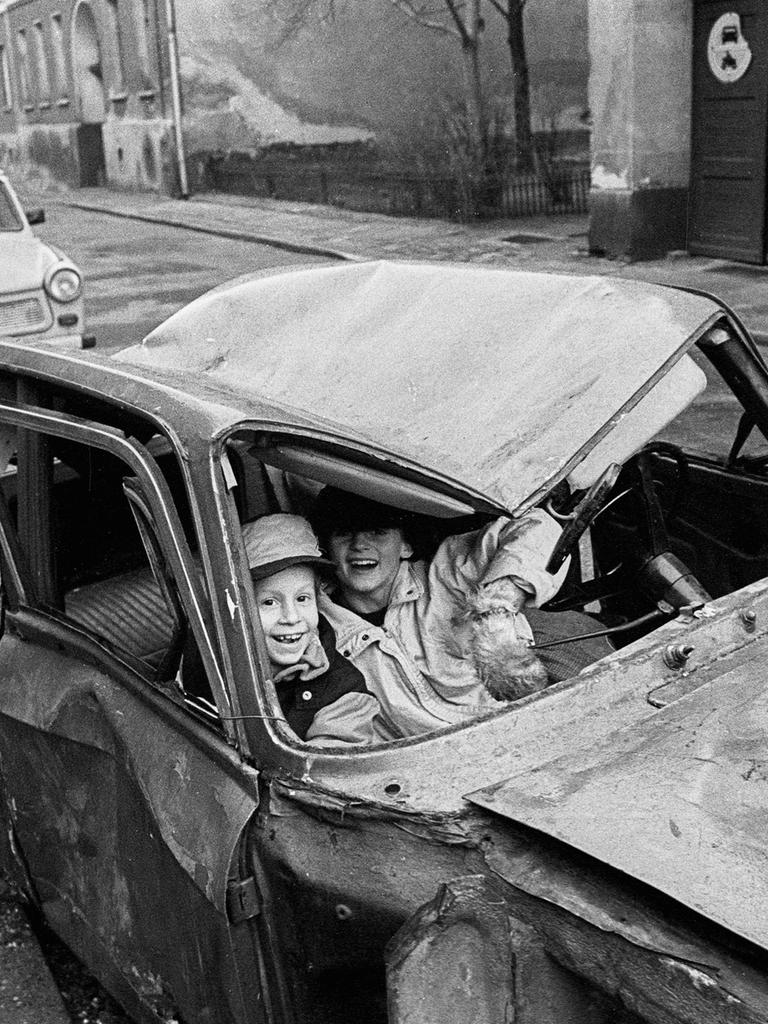 Lachende Kinder sitzen in einem Autowrack in der Steinstraße, Berlin 1990. Lachende Kinder sitzen in einem Autowrack in der Steinstraße, Berlin 1990.