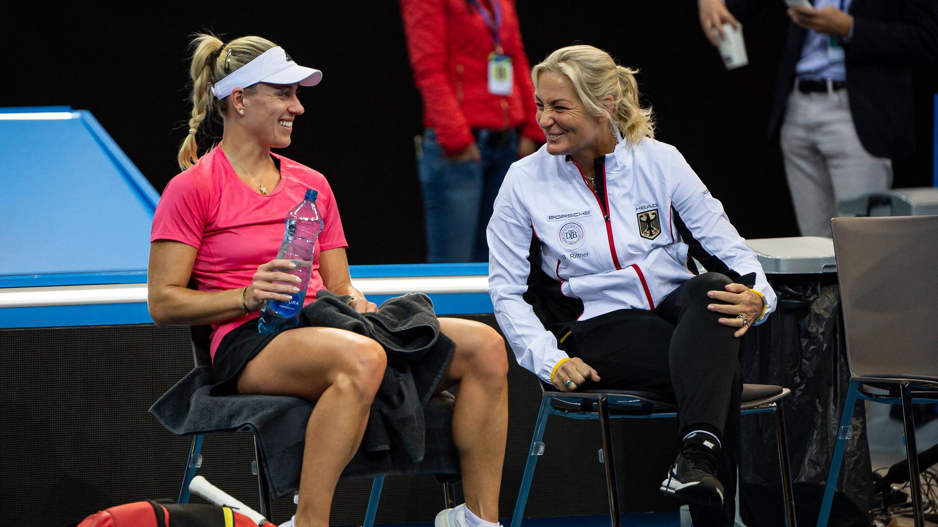 Tennis-Spielerin Angelique Kerber (l.) und Tennis-Bundestrainerin Barbara Ritter sitzen auf zwei Stühlen nebeneinander und unterhalten sich.