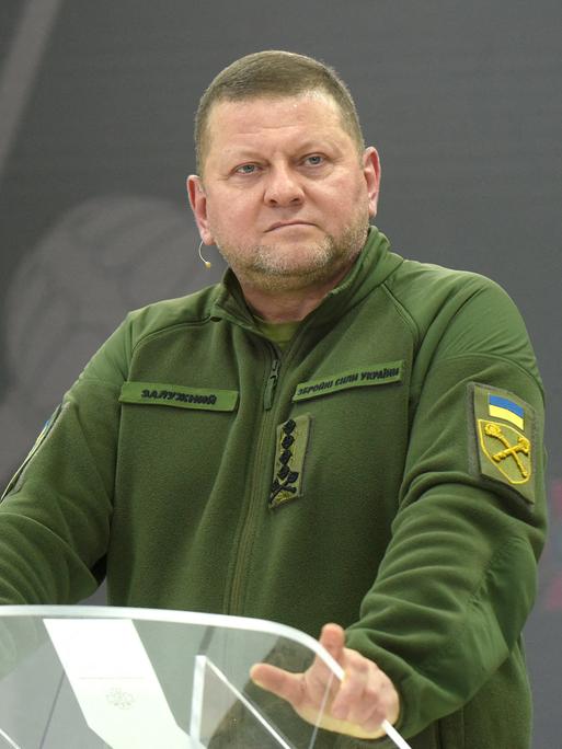 Der ehemalige Oberbefehlshaber der ukrainischen Streitkräfte, Walerij Saluschnyi steht in grüner Militärkleidung an einem Stehpult. 