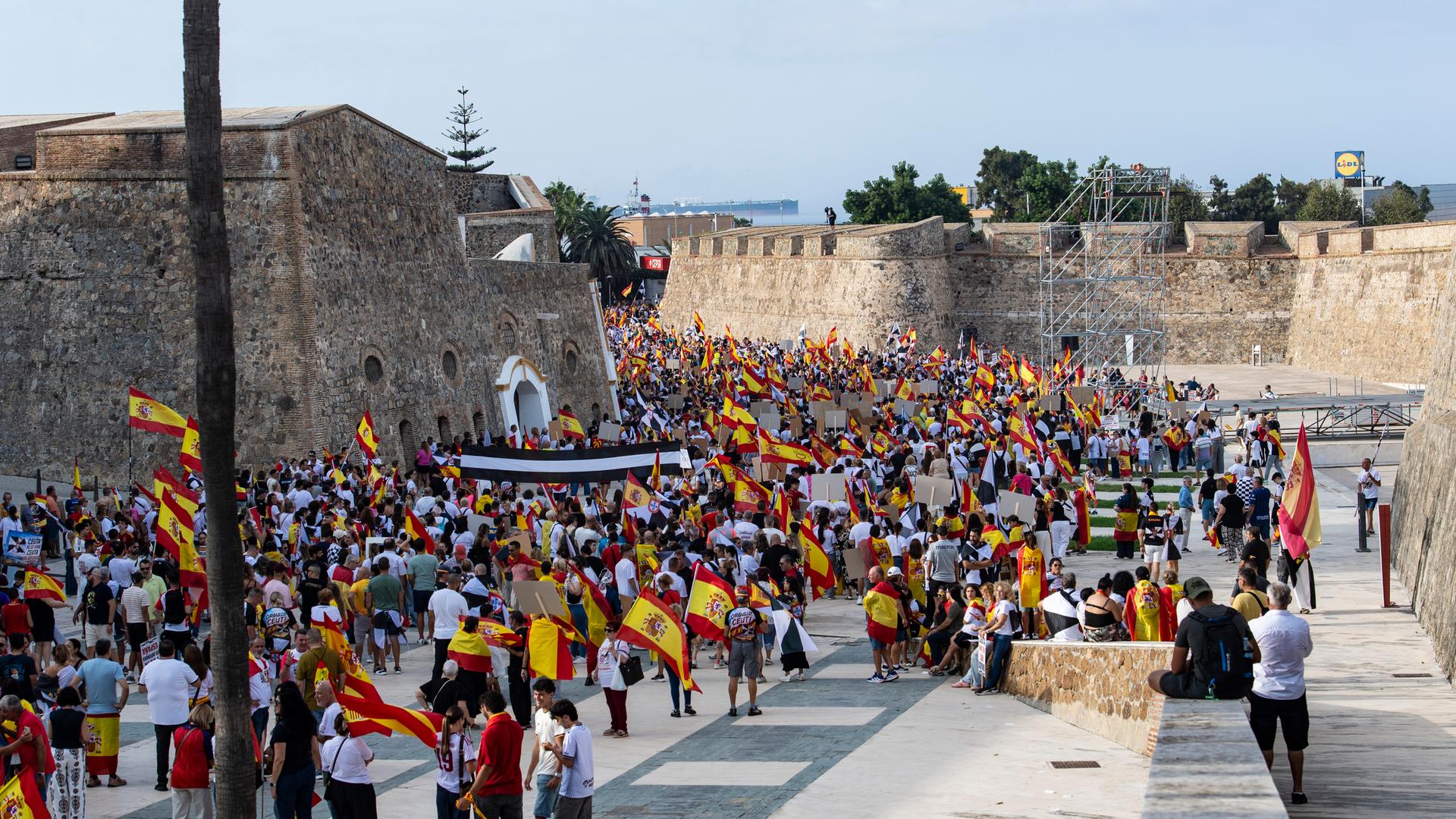 Zwischen alten Burgmauern haben sich viele Menschen versammelt, die spanische Flaggen tragen. Zwischen alten Burgmauern haben sich viele Menschen versammelt, die spanische Flaggen tragen.