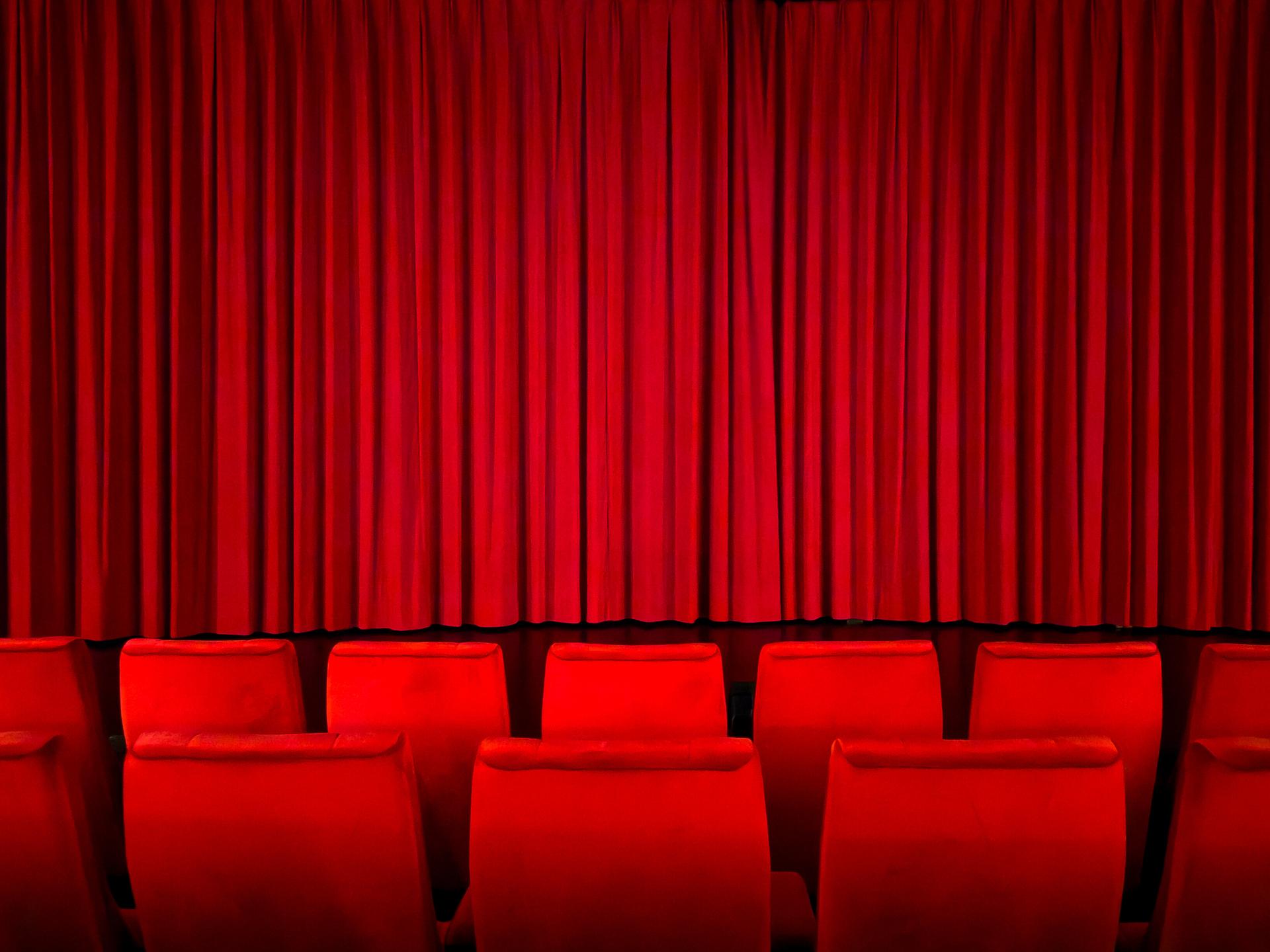 Ein roter Vorhang in einem Kinosaal vor der Vorstellung.