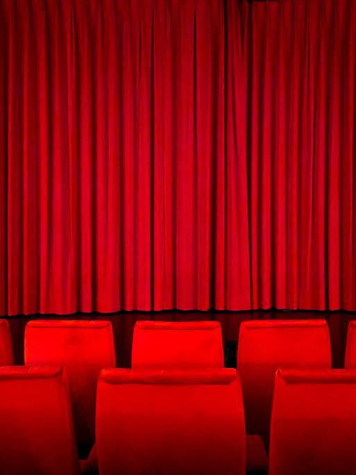 Ein roter Vorhang in einem Kinosaal vor der Vorstellung.