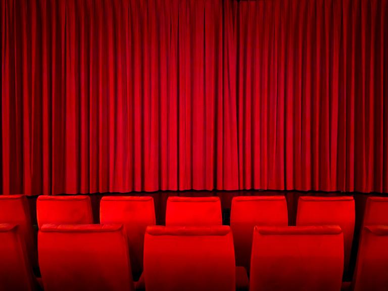 Ein roter Vorhang in einem Kinosaal vor der Vorstellung.