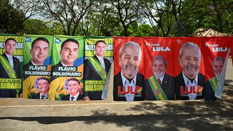 Wahlplakate von Lula da Silva und Flávio Bolsonaro nebeneinander an einer Wand.