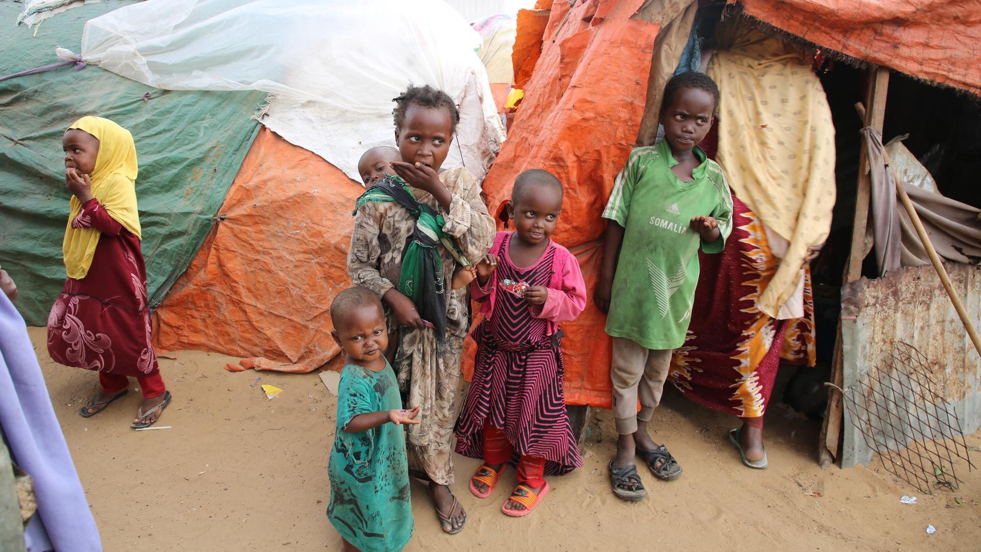 Mehrere Kinder stehen in Mogadischu vor provisorischen Stoffzelten. Mehrere Kinder stehen in Mogadischu vor provisorischen Stoffzelten.