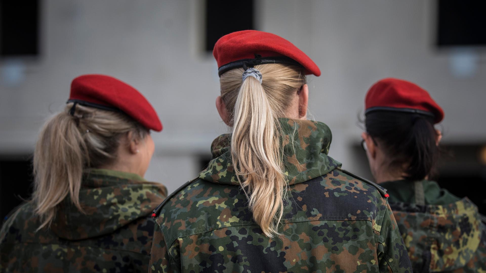 Drei Soldatinnen stehen mit dem Rücken zur Kamera. Sie tragen Bundes-Wehr-Uniformen.