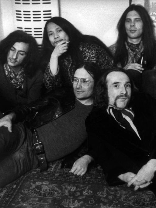 Sechs schwarz gekleidete Musiker der Band The Can posieren für ein Gruppenfoto.