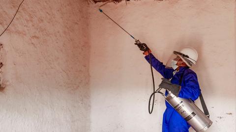 Ein Mosquito-Jäger spritzt Innenräume mit Insektiziden aus, damit sich keine Brutstätten bilden. Die Regierung bildet kommunale Gesundheitshelfer in den Dörfern aus. Malaria ist dank einer Vielzahl vom Maßnahmen auf dem Rückzug. 