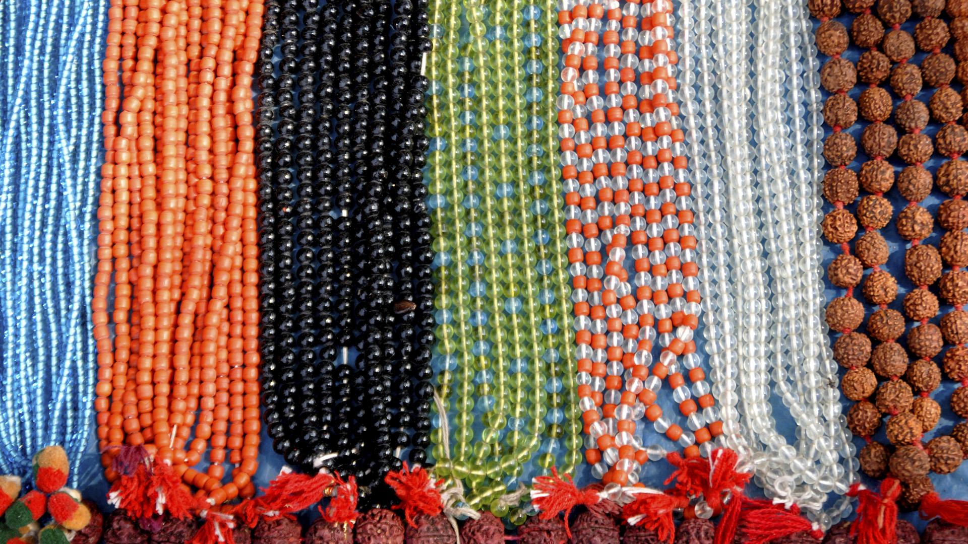 Buddhistische Gebetsketten, Mala, hängen in bunten Farben nebeneinander.