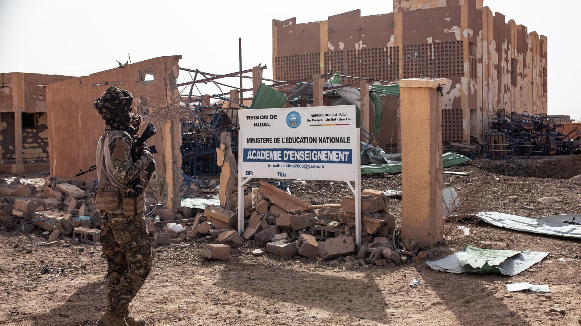 Ein Kämpfer der Befreiungsfront von Azawad (FLA) steht am 17. Mai 2026 vor dem zerstörten Gebäude der Regionalen Pädagogischen Hochschule in Kidal im Norden Malis. 