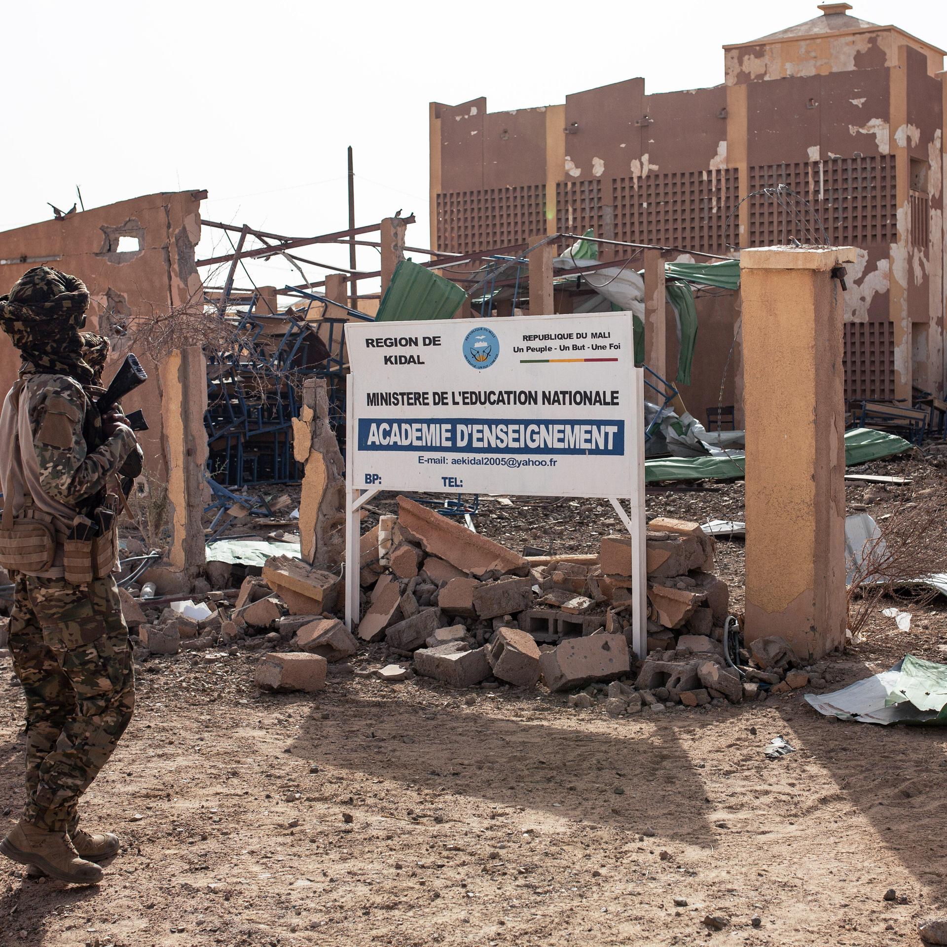 Ein Kämpfer der Befreiungsfront von Azawad (FLA) steht am 17. Mai 2026 vor dem zerstörten Gebäude der Regionalen Pädagogischen Hochschule in Kidal im Norden Malis. 