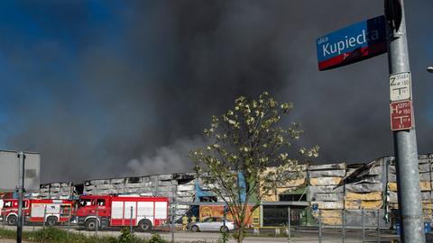 Das Foto zeigt das Warschauer Einkaufszentrum, eine große Rauchwolke und Feuerwehrautos.