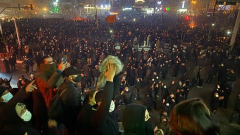 Auf dem Bild sind zahlreiche Menschen zu sehen, die nachts in einer Straße in Teheran demonstrieren. Einige halten Transparente hoch. 