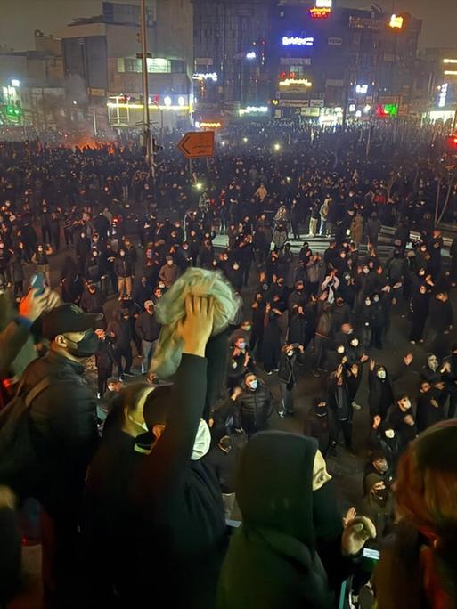 Auf dem Bild sind zahlreiche Menschen zu sehen, die nachts in einer Straße in Teheran demonstrieren. Einige halten Transparente hoch. 