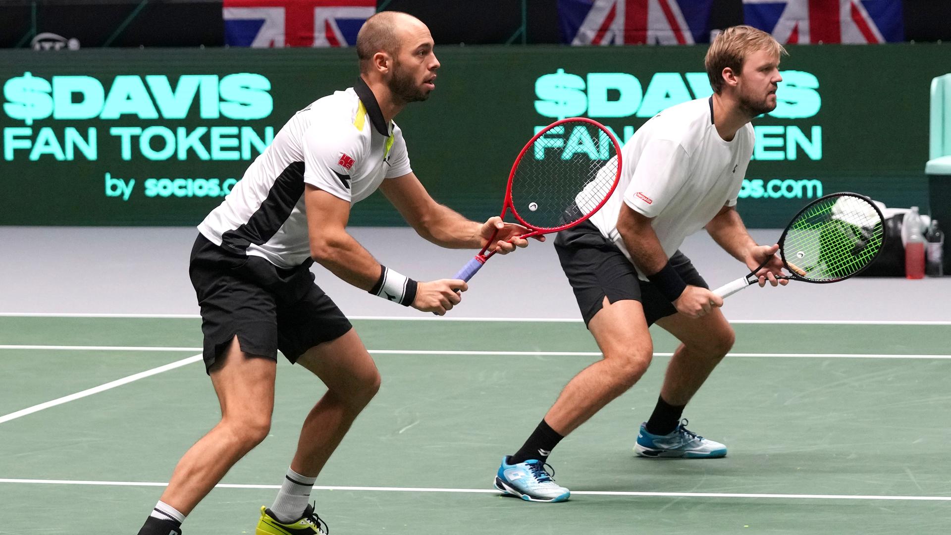 Zwei Tennisspieler erwarten mit gespannten Gesichtern den Ball.