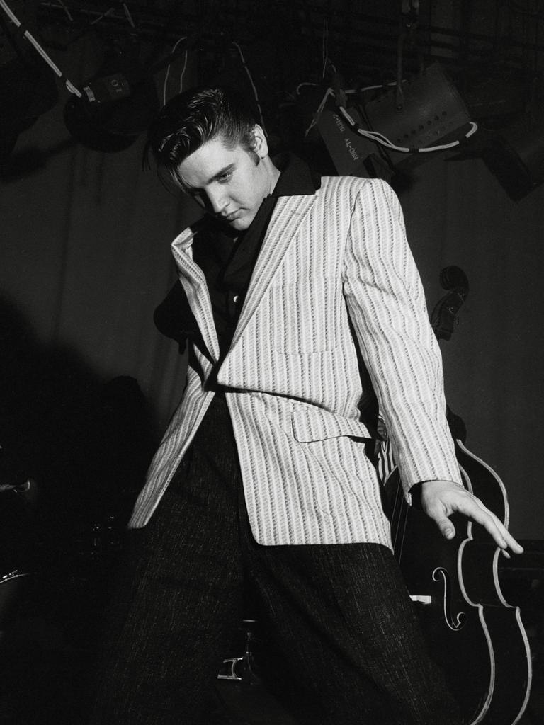 Schwarz-Weiß-Aufnahme von Elvis Presley, der lässig-lasziv an seiner Gitarre lehnt