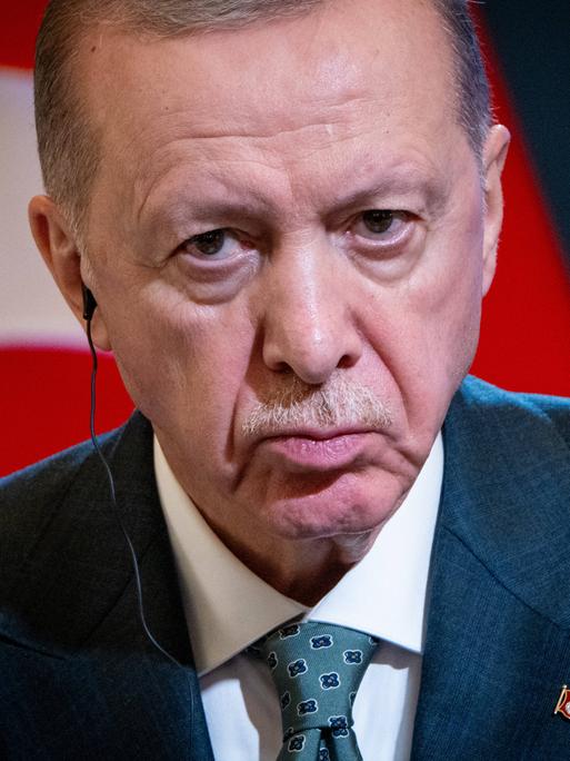 Porträt des türkischen Präsodenten Erdogan, der grimmig in die Kamera guckt. Im Hintergrund sind Teile der türkischen Flagge zu erkennen. Porträt des türkischen Präsodenten Erdogan, der grimmig in die Kamera guckt. Im Hintergrund sind Teile der türkischen Flagge zu erkennen.
