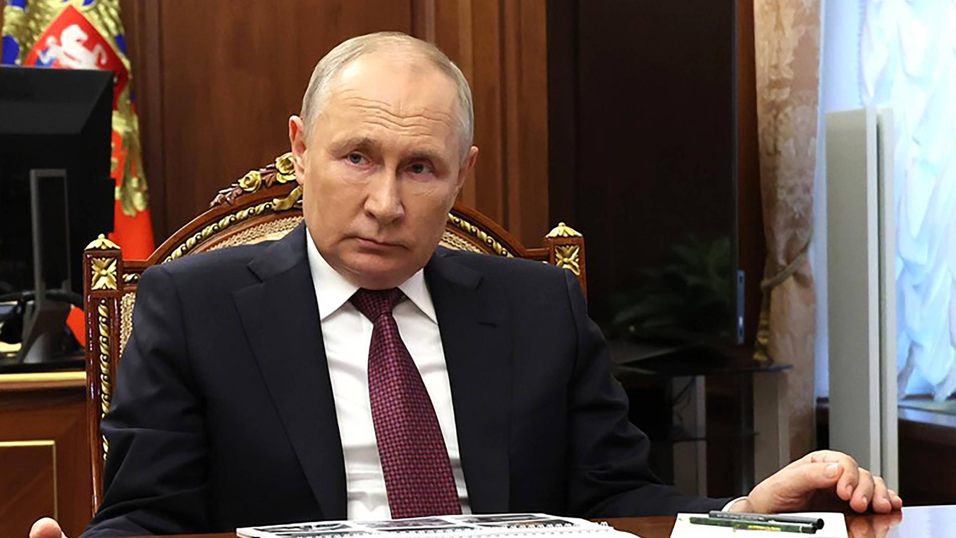 Präsident Putin sitzt an einem Tisch an seinem Regierungsort.