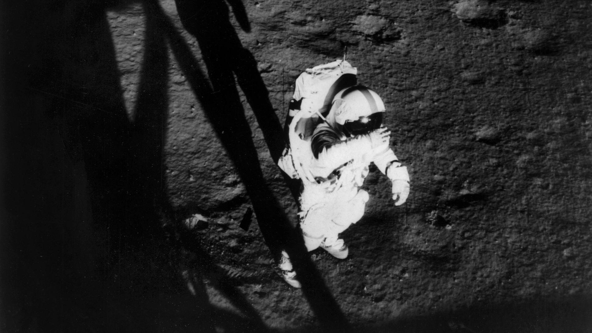 Schwarzweißfoto von Alan Shephard, der in voller Montur auf der Mondoberfläche steht