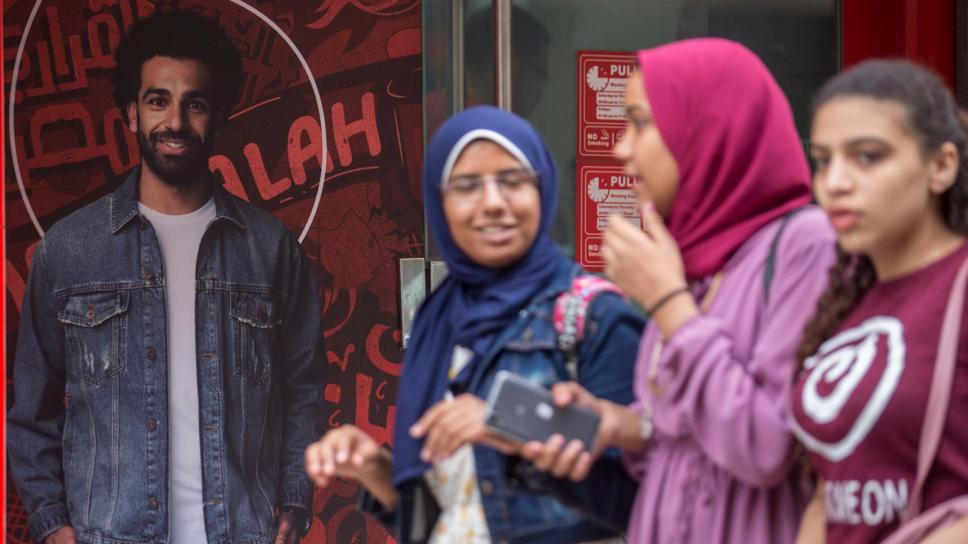 03.05.2018, Ãgypten, Kairo: Drei Mädchen gehen in Kairo an einer Werbung eines Telekommunikationsunternehmens mit dem ägyptischen Liverpool-Star Mohamed Salah vorbei. Foto: Gehad Hamdy/dpa 03.05.2018, Ãgypten, Kairo: Drei Mädchen gehen in Kairo an einer Werbung eines Telekommunikationsunternehmens mit dem ägyptischen Liverpool-Star Mohamed Salah vorbei. Foto: Gehad Hamdy/dpa