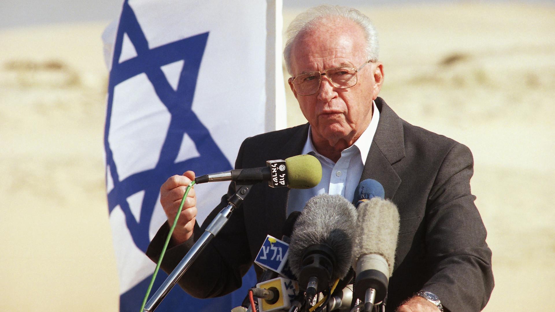 Israeli Prime Minister Yitzhak Rabin spricht 1994 vor einer israelischen Flagge in Mikrofone und hält eine geballte Faust hoch Israeli Prime Minister Yitzhak Rabin spricht 1994 vor einer israelischen Flagge in Mikrofone und hält eine geballte Faust hoch