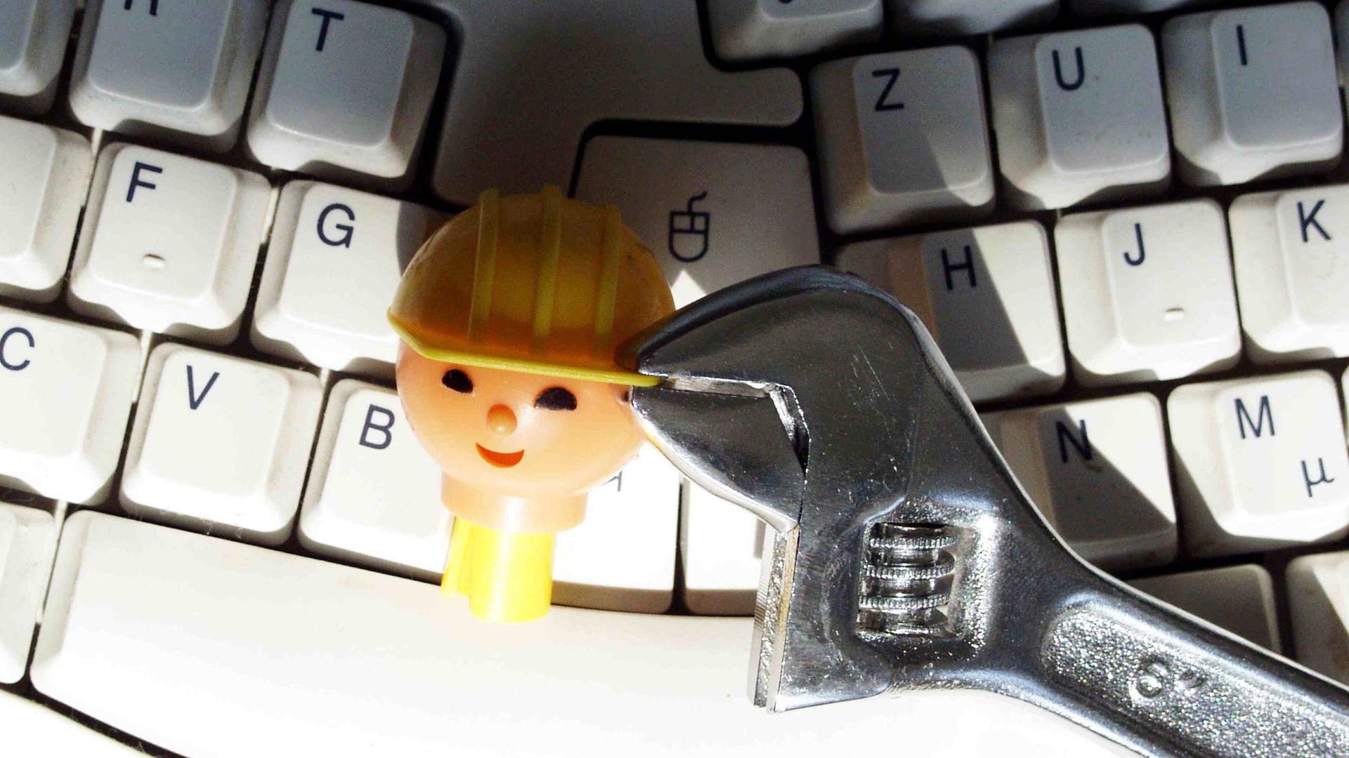 Kopf einer Playmobil-Bauarbeiter-Figur wird auf einer Tastatur mit einer Zange festgehalten Kopf einer Playmobil-Bauarbeiter-Figur wird auf einer Tastatur mit einer Zange festgehalten