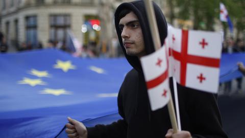 Demonstrant mit georgischen Flaggen und EU-Fahne. 