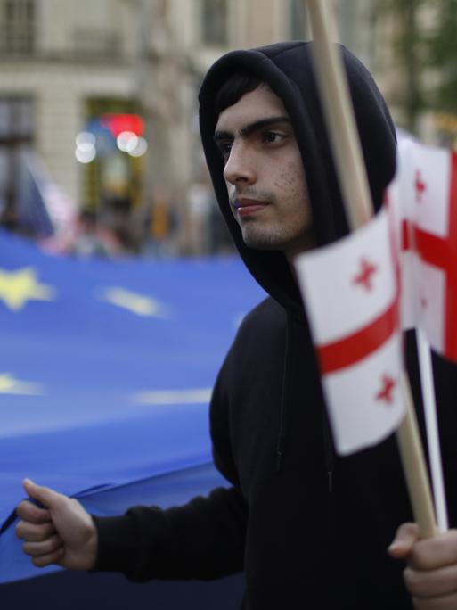 Demonstrant mit georgischen Flaggen und EU-Fahne. 