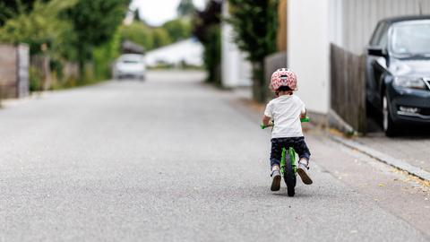 Ein 5-jähriges Mädchen fährt einem Kinderlaufrad zu einem Spielplatz.