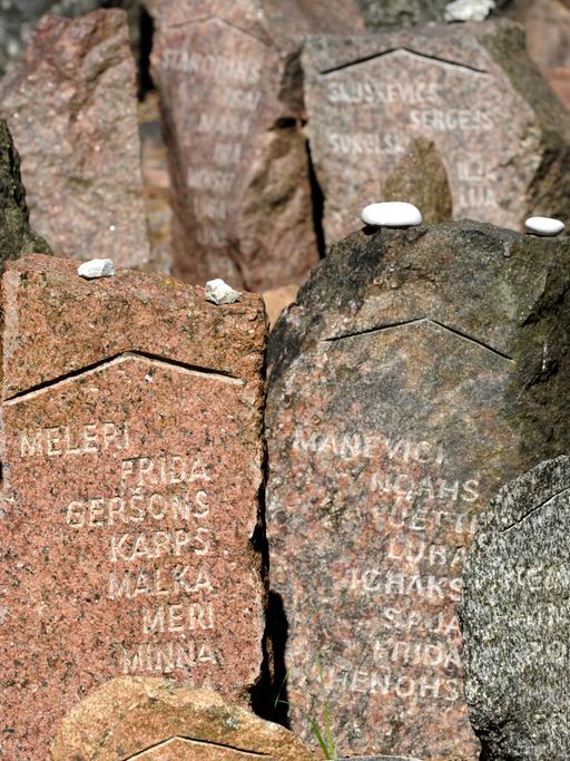 Mit Namen versehene Gedenksteine im Wald von Rumbula nahe Riga. An dieser Stelle erschossen deutsche Truppen 1941  mehr als 27.000 Jüdinnen und Juden