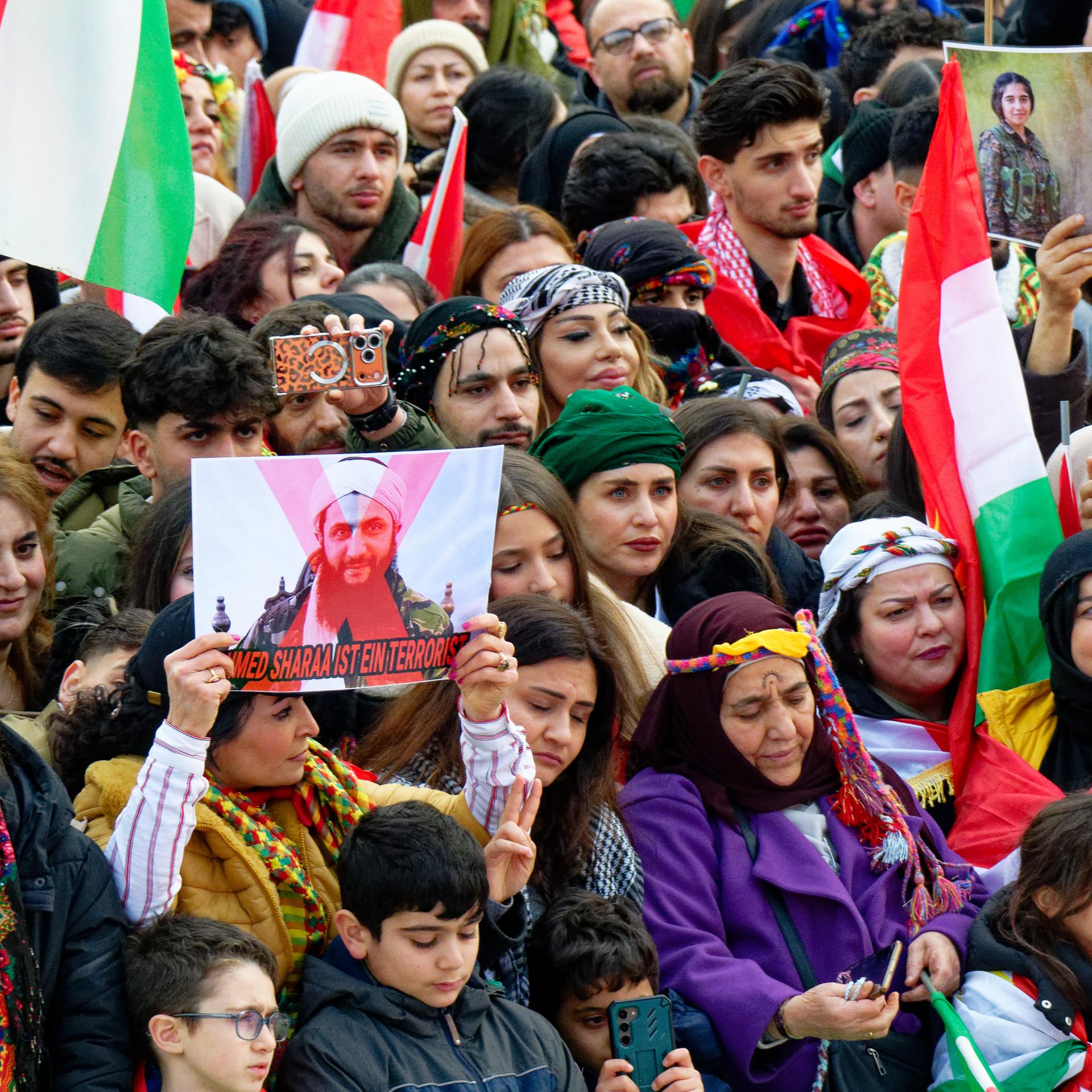 Teilnehmer einer Demonstration halten Fahnen hoch.