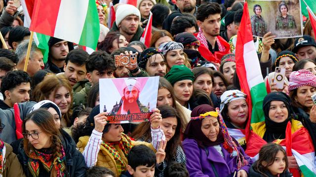 Teilnehmer einer Demonstration halten Fahnen hoch.