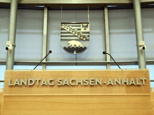 Hinter dem Rednerpult im Plenarsaal des Landtages von Sachsen-Anhalt hängt das sachsen-anhaltinische Wappen mit Adler und Bär.