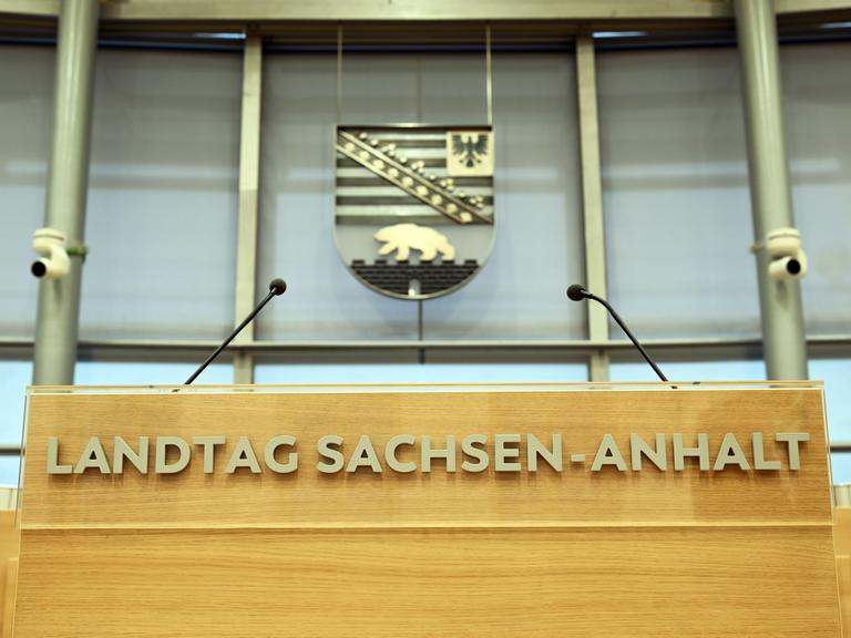 Hinter dem Rednerpult im Plenarsaal des Landtages von Sachsen-Anhalt hängt das sachsen-anhaltinische Wappen mit Adler und Bär.