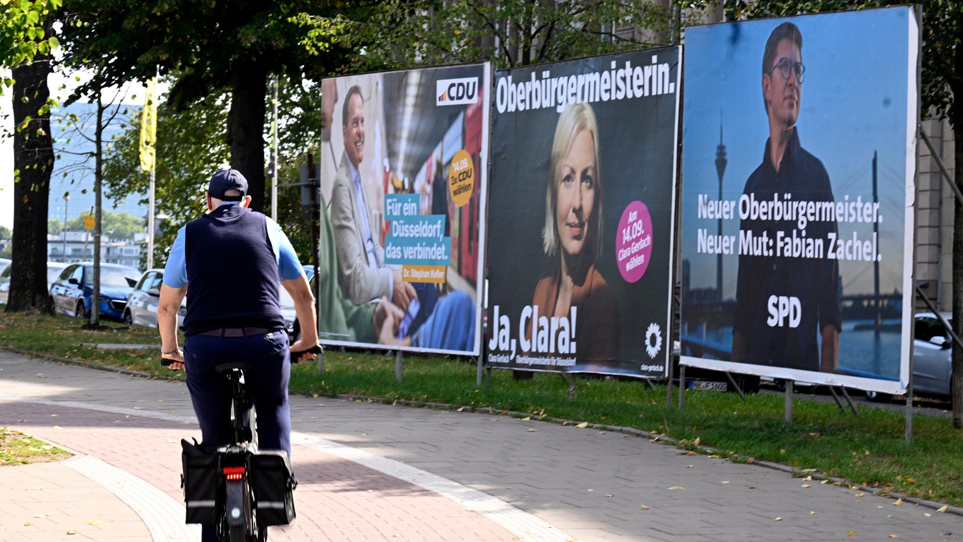 Ein Radfahrer fährt vor der Kommunalwahl in Nordrhein-Westfalen an den Wahlplakaten der Parteien in Düsseldorf-Oberkassel vorbei. 