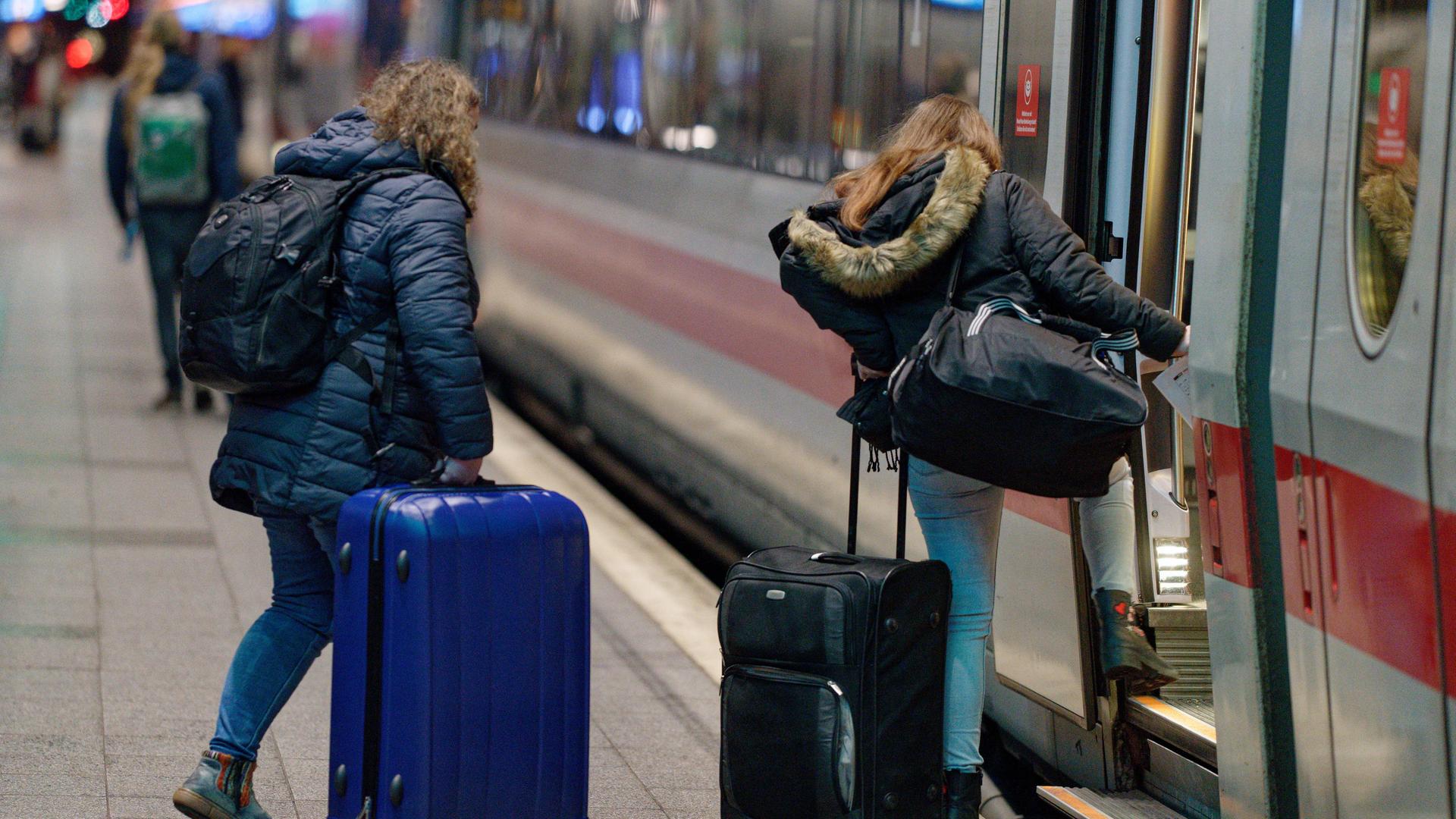 Reisende steigen an einem Bahnhof in einen ICE.