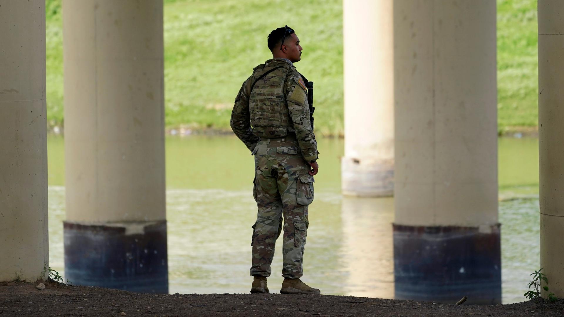 Ein Soldat in Uniform blickt am Eagle Pass über den Rio Grande nach Mexiko. Ein Soldat in Uniform blickt am Eagle Pass über den Rio Grande nach Mexiko.